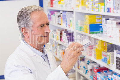 Senior pharmacist taking medicine from shelf