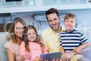 Happy family on the couch together using tablet