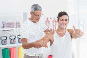 Doctor stretching a young man arm with thumb up