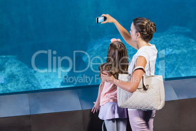 Happy mother and daughter taking photo of fish