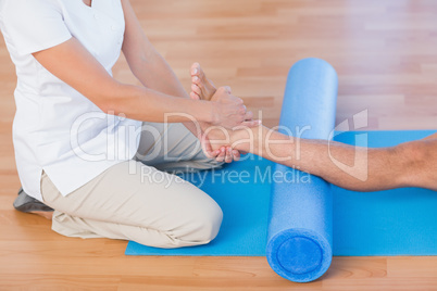 Trainer working with man on exercise mat