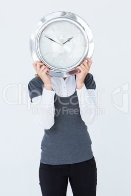 Woman holding clock in front of her head