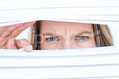 Woman peering through roller blind