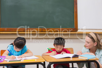 Cute pupils getting help from teacher in classroom