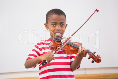 Happy pupil playing violin in classroom