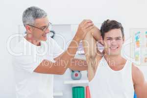 Doctor stretching a young man arm