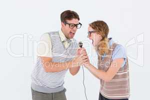 Geeky hipster couple singing into a microphone