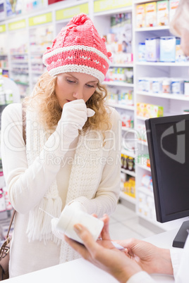 Sick girl with scarf and colorful hat giving bottle of drug