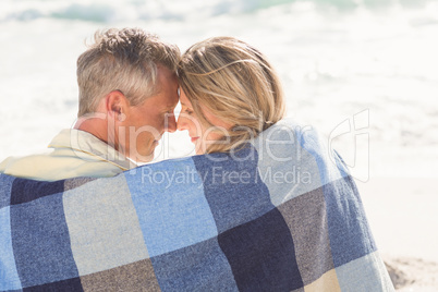 Happy couple wrapped up in blanket