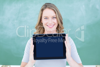 Smiling teacher holding tablet pc in front of blackboard