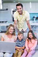 Happy family on the couch together using laptop