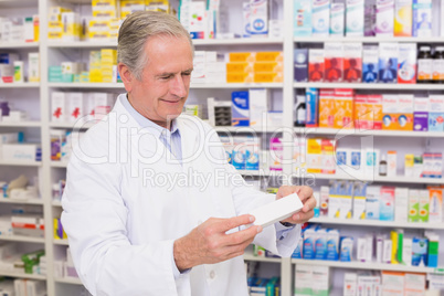 Pharmacist holding a box of pills while reading the label