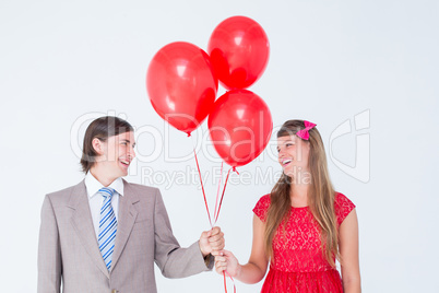 Smiling geeky couple holding red balloons