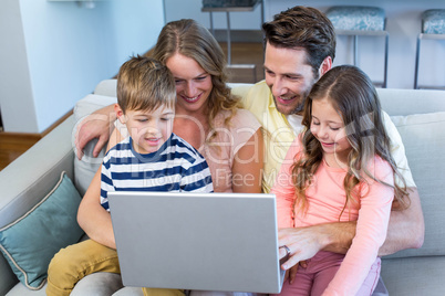 Happy family on the couch together using laptop