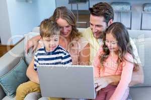 Happy family on the couch together using laptop