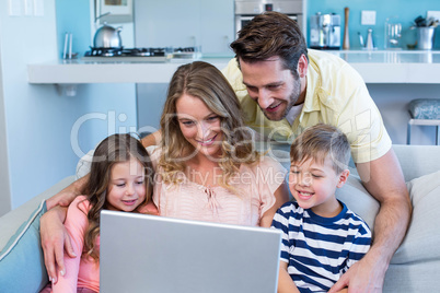 Happy family on the couch together using laptop Happy family on the couch together using laptop