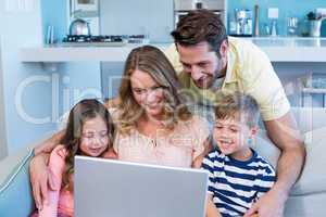 Happy family on the couch together using laptop