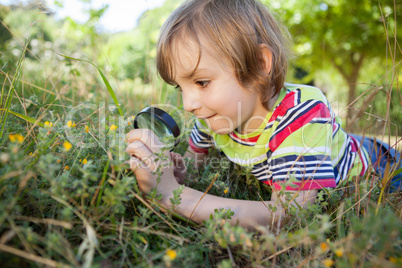 Happy little boy looking through magnifying glass