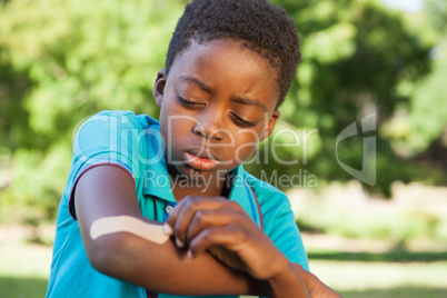 Little boy putting plaster on arm