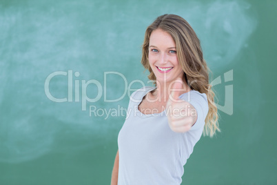 Smiling teacher standing thumbs up in front of blackboard