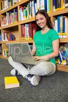 Student sitting on floor in library using laptop