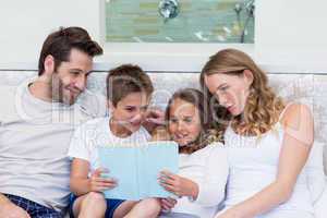 Happy family on the bed reading book