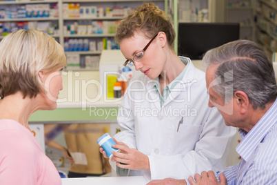 Pharmacist holding a bottle of drugs talking to customer