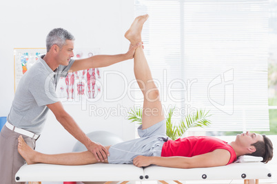 Physiotherapist doing leg stretching to his patient