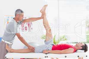 Physiotherapist doing leg stretching to his patient