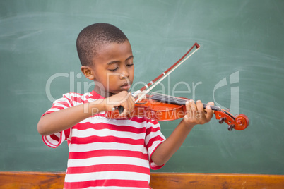 Cute pupil playing violin in classroom