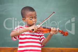 Cute pupil playing violin in classroom
