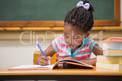 Cute pupils writing at desk in classroom