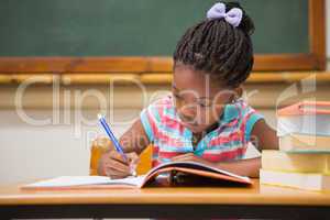 Cute pupils writing at desk in classroom