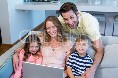 Happy family on the couch together using laptop