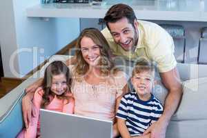 Happy family on the couch together using laptop