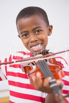 Happy pupil playing violin in classroom