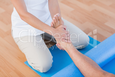 Trainer working with man on exercise mat