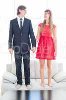 Geeky couple standing hand in hand on the couch