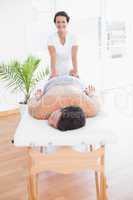 Patient relaxing on the massage table with physiotherapist behin