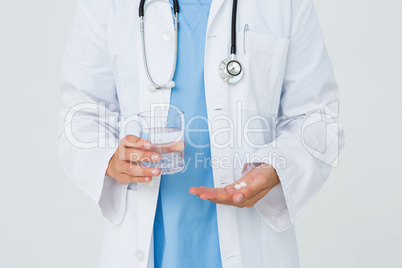 Doctor holding glass of water and pills