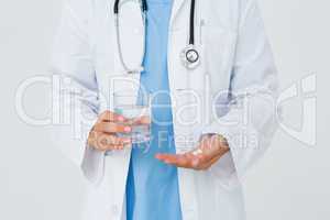 Doctor holding glass of water and pills