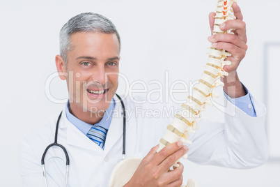 Smiling doctor showing anatomical spine