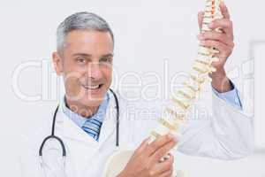 Smiling doctor showing anatomical spine