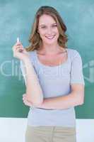 Woman in front of a blackboard holding a piece of chalk