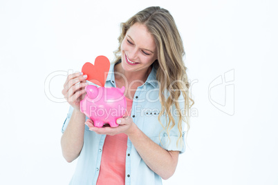 Smiling woman holding piggy bank and red heart Smiling woman holding piggy bank and red heart