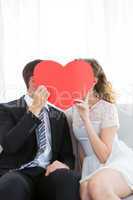 Couple kissing behind heart card