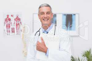 Happy doctor holding clipboard and smiling at camera