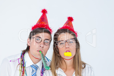 Geeky hipster wearing a party hat with blowing party horn