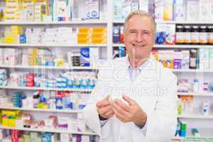 Smiling pharmacist holding a box of pills