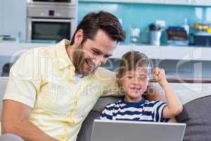 Father and son using laptop on the couch